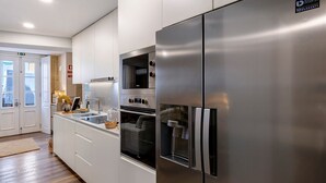 A modern kitchen with a stainless steel refrigerator, oven, and microwave. - Casa ao Lado – In the Heart of Ponte de Lima with Private Entrance and Full Comfort (Ponte de Lima)