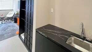A modern kitchen with a black marble countertop and a stainless steel sink.