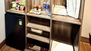 A walk-in closet with wooden shelving, a hanging robe, and a small refrigerator.