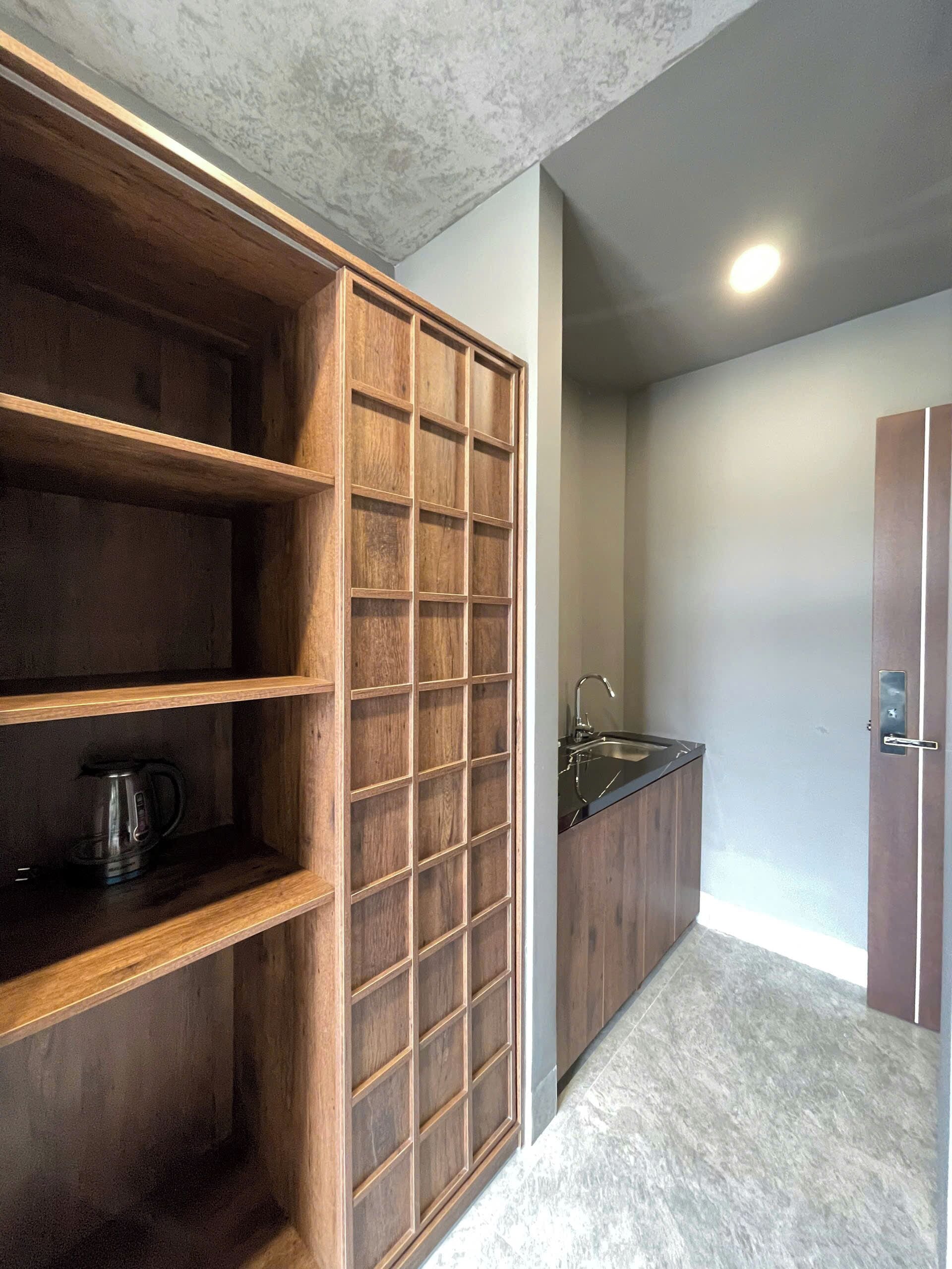 A modern kitchen with wooden cabinetry, a built-in coffee maker, and a stainless steel sink.