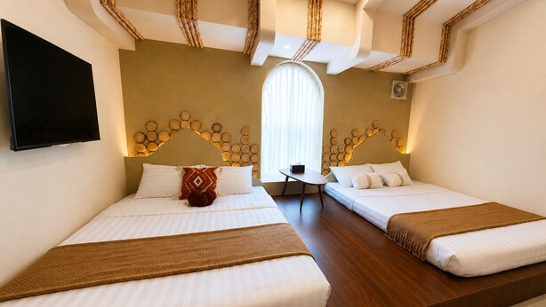 A hotel room with two beds, a small table, a TV, and a large window. - Min Min Retreat Homestay (Hue)