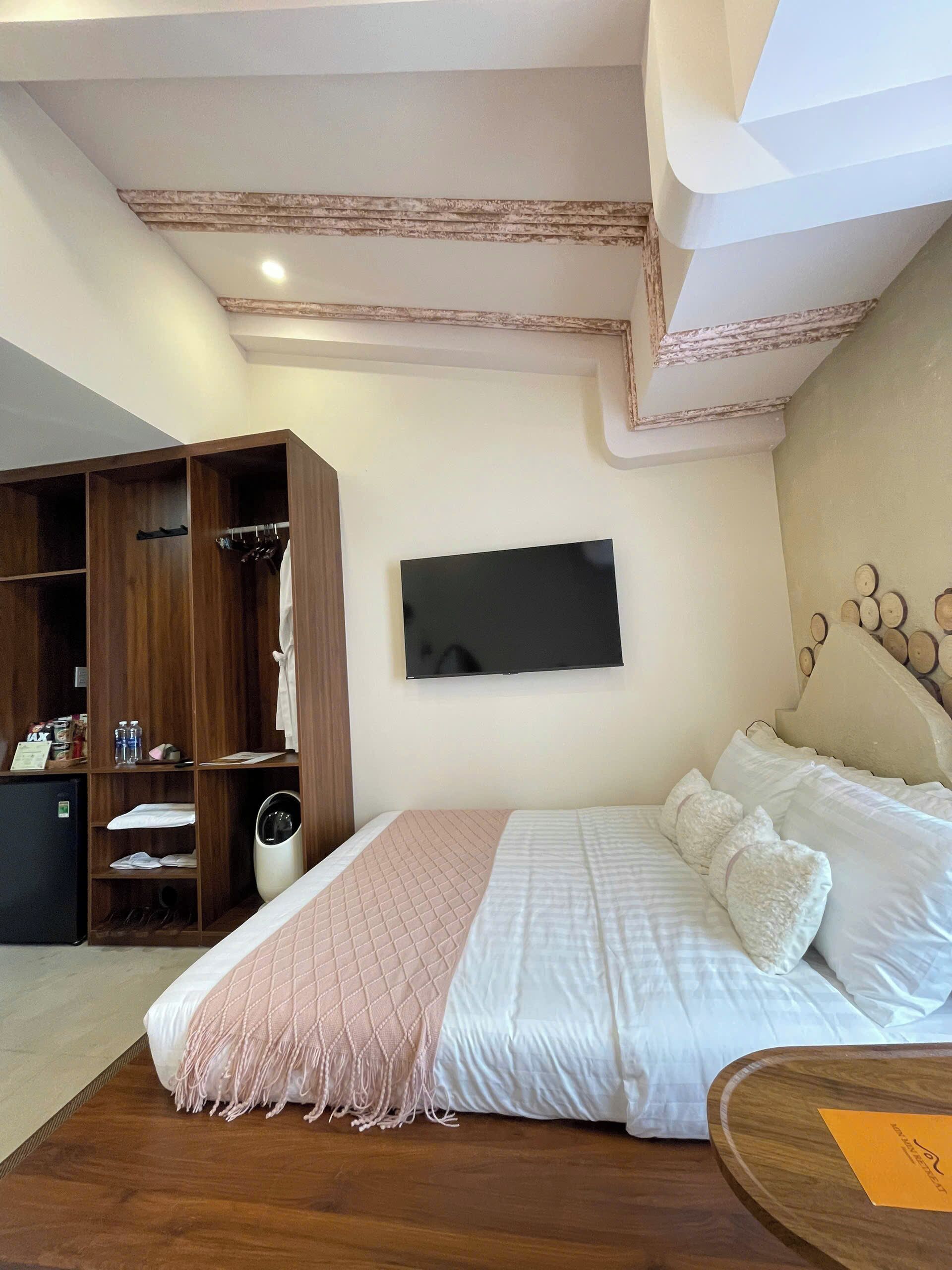 A bedroom with a bed, a wardrobe, a television, and a small table.