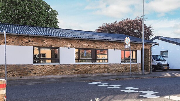 A building with a brick facade, large windows, and a parking area. - 4 Star Holiday Home in Skagen (Skagen)