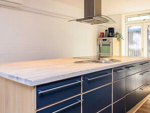 A modern kitchen with a wooden countertop, stainless steel sink, and dark cabinetry. - 4 Star Holiday Home in Skagen (Skagen)