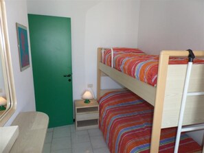 A bunk bed with striped bedding, a green door, a small bedside table with a lamp, and a mirror. - Apartment near the beach with town views (Bibione)