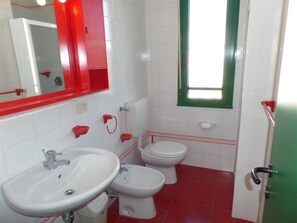 A bathroom with a sink, two toilets, a mirror, and a window. - Apartment near the beach with town views (Bibione)