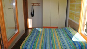 A bedroom with a bed, wardrobe, and a hanging bag. - Comfortable vacation retreat in a central area (Bibione)