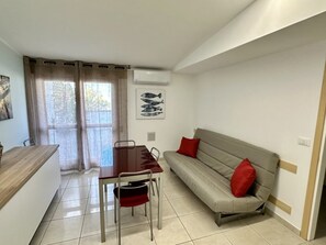 Ein gemütlicher Wohnbereich mit Esstisch, einer Couch und einem Vorhangfenster.
