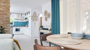 A modern kitchen with white cabinets, a blue backsplash, and a dining area with a round table and wooden chairs. - Perfect 2-bedroom lodge with AC in peaceful Balatonmáriafürdő (Balatonmáriafürdő)