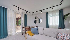 A modern living room with a sofa, a dining table, and a sliding glass door leading to an outdoor area. - Perfect 2-bedroom lodge with AC in peaceful Balatonmáriafürdő (Balatonmáriafürdő)
