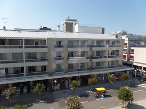A multi-story hotel with balconies, a ground floor with shops, and a street view with pedestrians and vehicles. - Sunny accommodation with rooftop pool (Bibione)