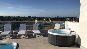 A rooftop terrace with a hot tub, lounge chairs, and a swimming pool. - Sunny accommodation with rooftop pool (Bibione)
