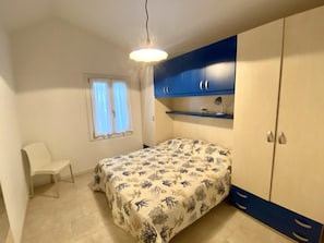 Ein Schlafzimmer mit Bett, Sessel, Schreibtisch und Kleiderschrank.