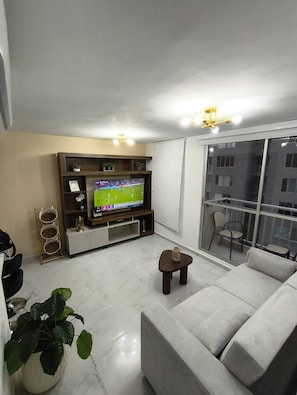 Un salon avec un téléviseur, un canapé et un balcon offrant une vue agréable.