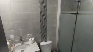 A bathroom with a toilet, sink, and a glass shower enclosure. - Your Home in Barranquilla (Barranquilla)