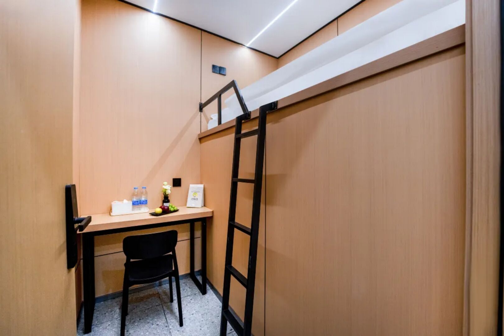 A small room with a desk, chair, and a ladder against the wall.