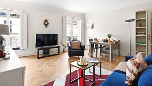 A living room with a TV, a dining area, and a sofa. - Chic 1BR Near Opéra & Louvre (Paris)