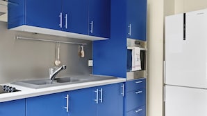 A kitchen with blue cabinets, a white sink, and a white refrigerator. - Chic 1BR Near Opéra & Louvre (Paris)
