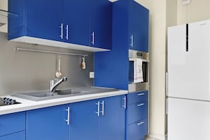 Eine Küche mit blauen Schränken, einer weißen Spüle und einem weißen Kühlschrank.