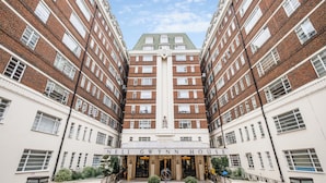 Un hôtel à plusieurs étages, doté d’une entrée centrale, d’une façade en briques et de fenêtres disposées de manière symétrique.