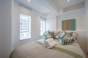 Ein Schlafzimmer mit einem Bett, Kissen, einem Fenster und einem Wandbild.