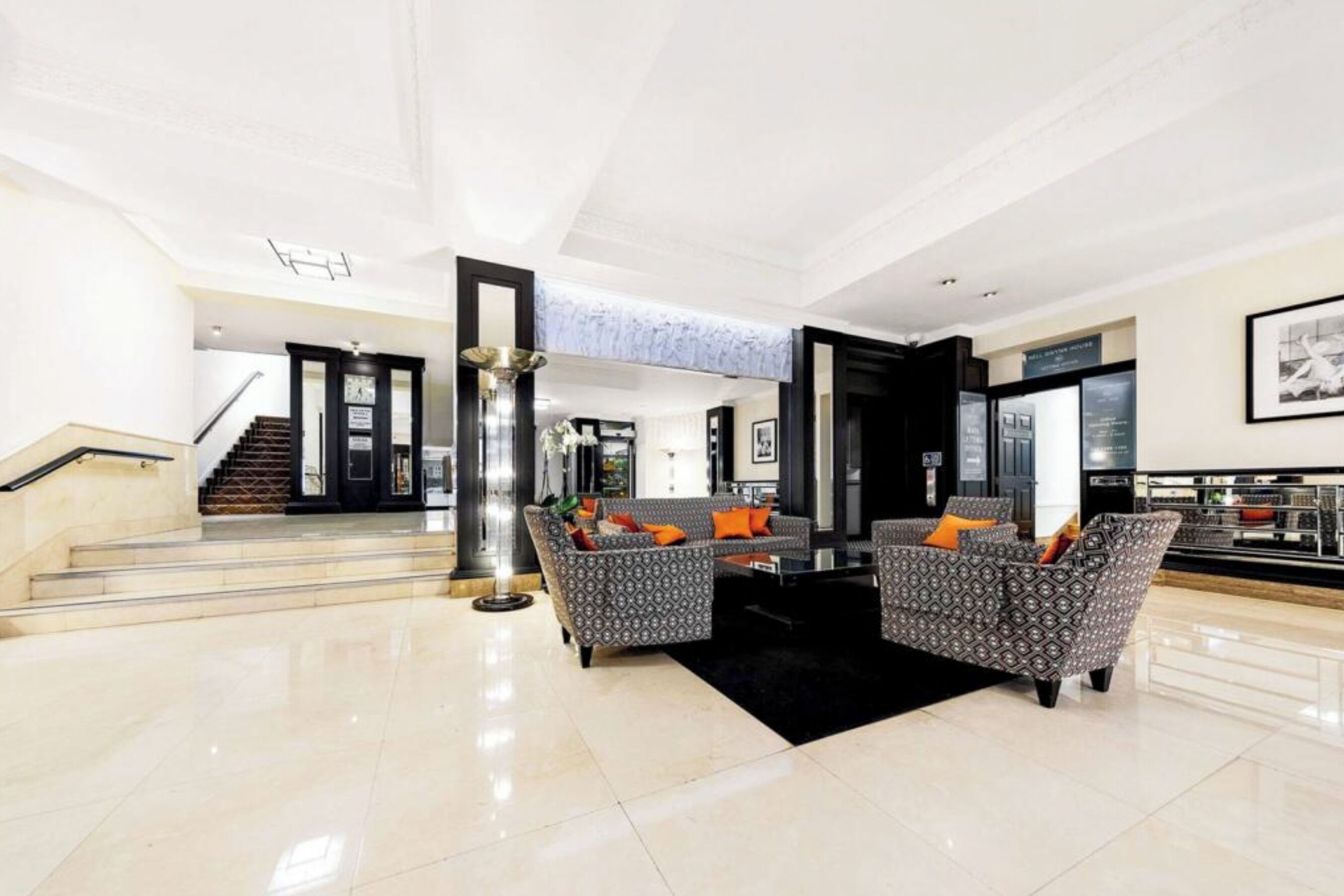 Eine geräumige Lobby mit Treppe, gestreiften Sofas und einem schwarzen Teppich.