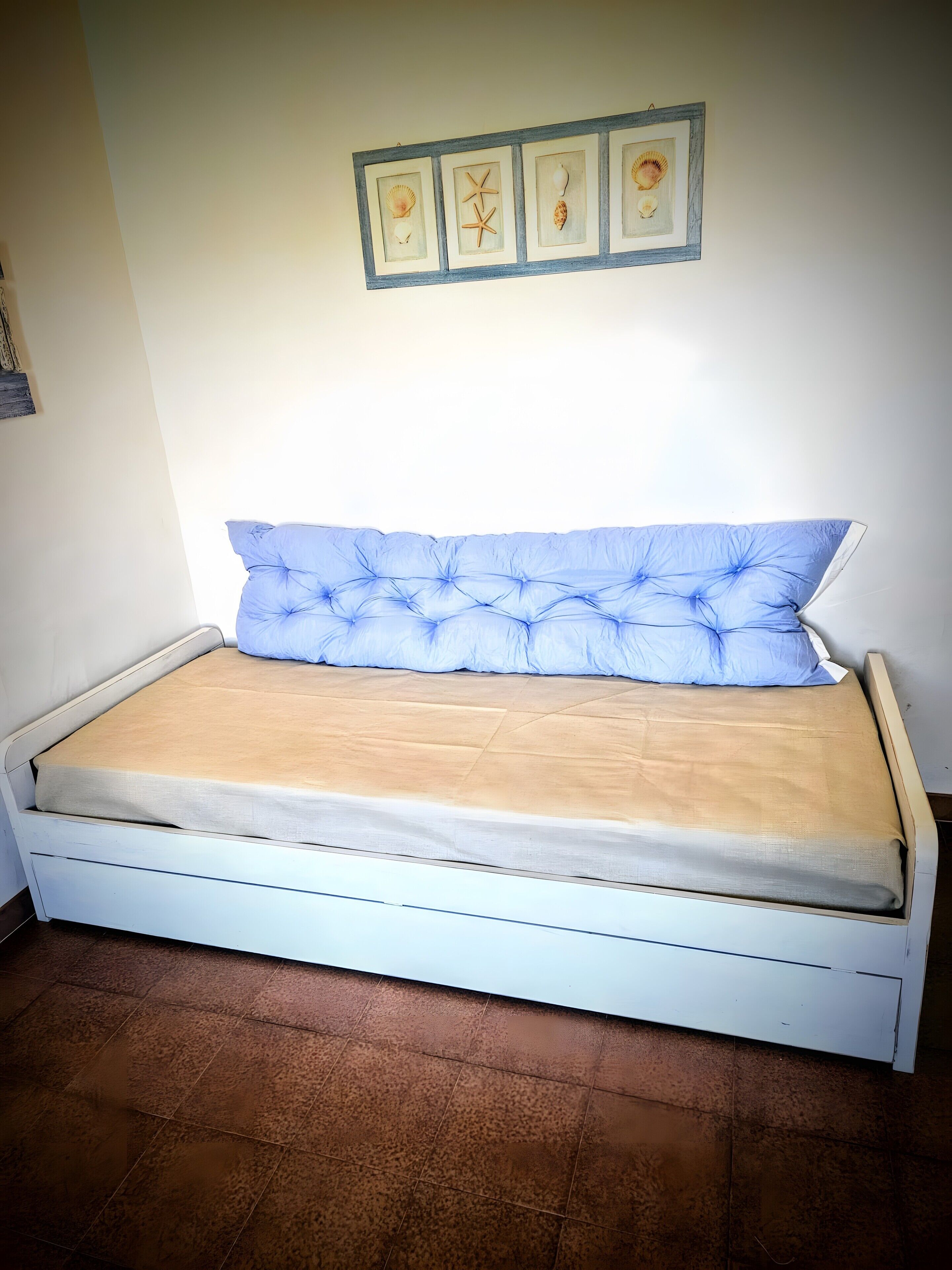 Ein Bett mit einem geblümten Kopfteil, einer beigen Matratze und einem weißen Rahmen.