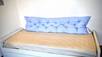 Ein Bett mit einem geblümten Kopfteil, einer beigen Matratze und einem weißen Rahmen.