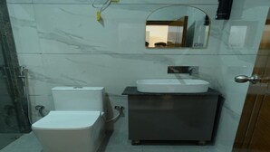 A bathroom with a toilet, a sink, and a mirror. - Hotel Deep Khirsu (Khirsu)