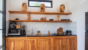 Cocina moderna con armarios de madera, microondas, cafetera y objetos decorativos en estantes.