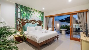 Un dormitorio con una cama, un mural en la pared, una puerta corrediza de vidrio a un balcón y una pequeña mesa con sillas.