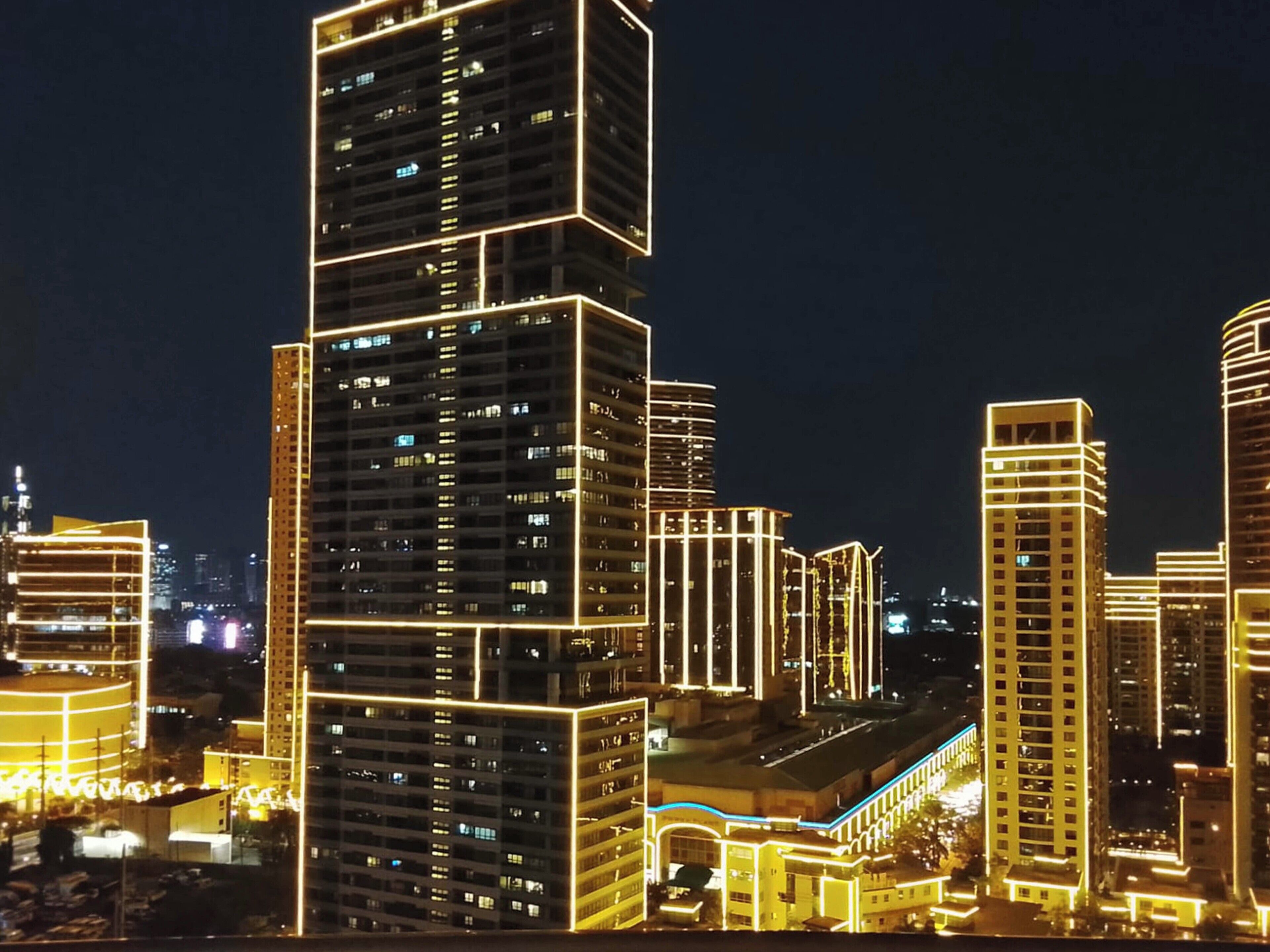 Une vue nocturne d’une ville, avec des gratte-ciel illuminés.