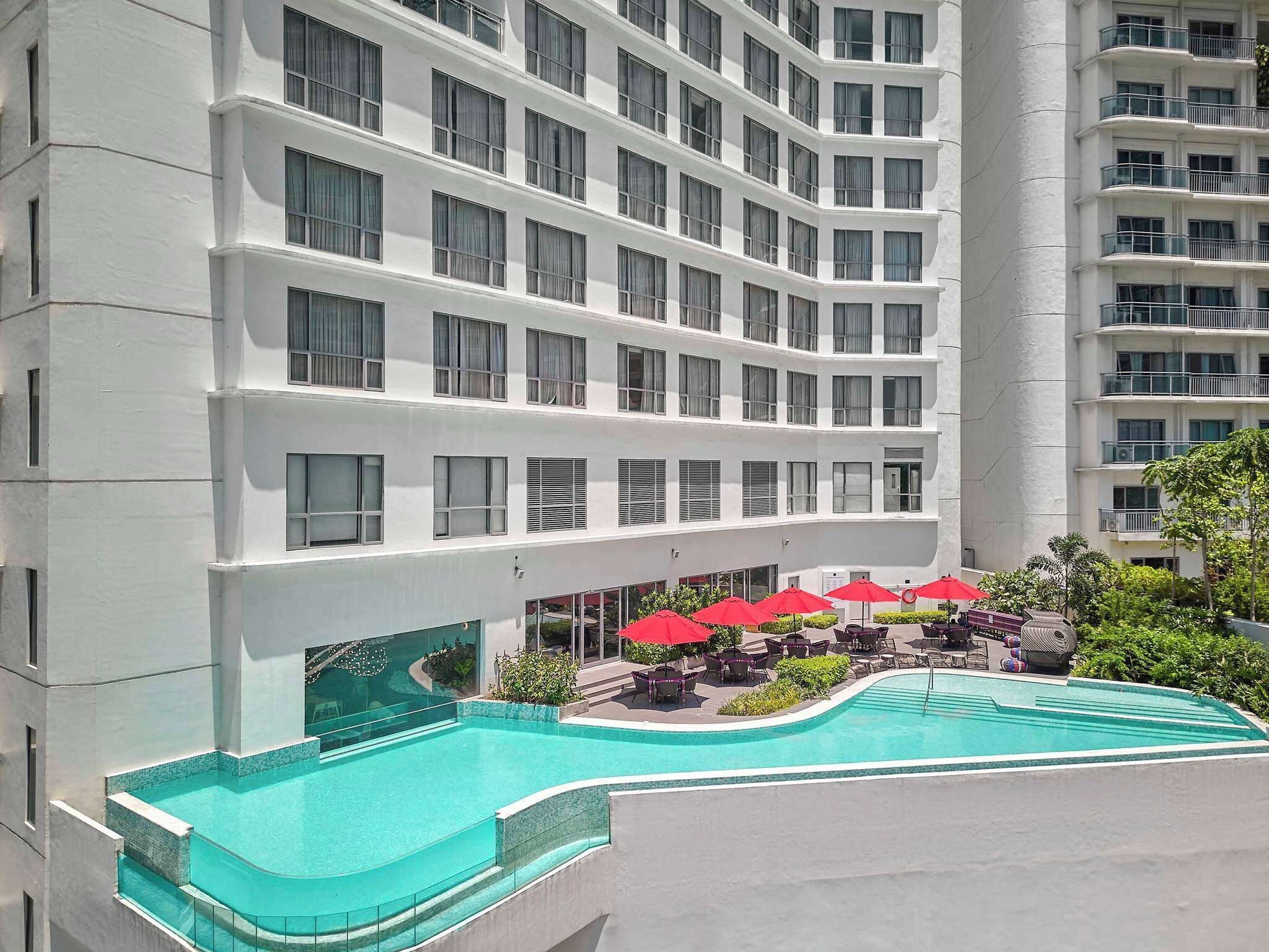 Un hotel a più piani con piscina, area salotto all'aperto e un'imponente colonna centrale.