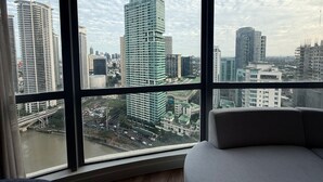 A room with a large window offering a view of a cityscape with high-rise buildings. - Novotel Suites at Acqua (Mandaluyong)