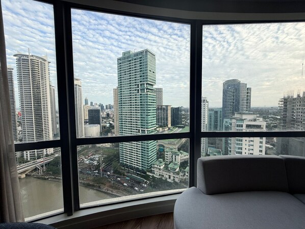 Ein Zimmer mit großem Fenster und Blick auf eine Skyline mit Hochhäusern.