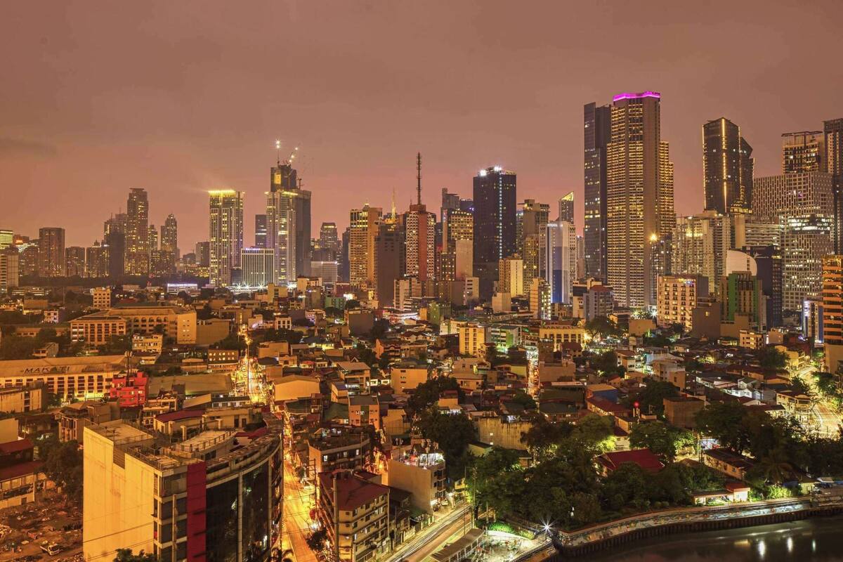 A nighttime cityscape with high-rise buildings and a river.