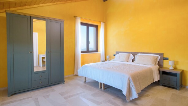 Un dormitorio con cama, mesitas de noche, un armario y una ventana.