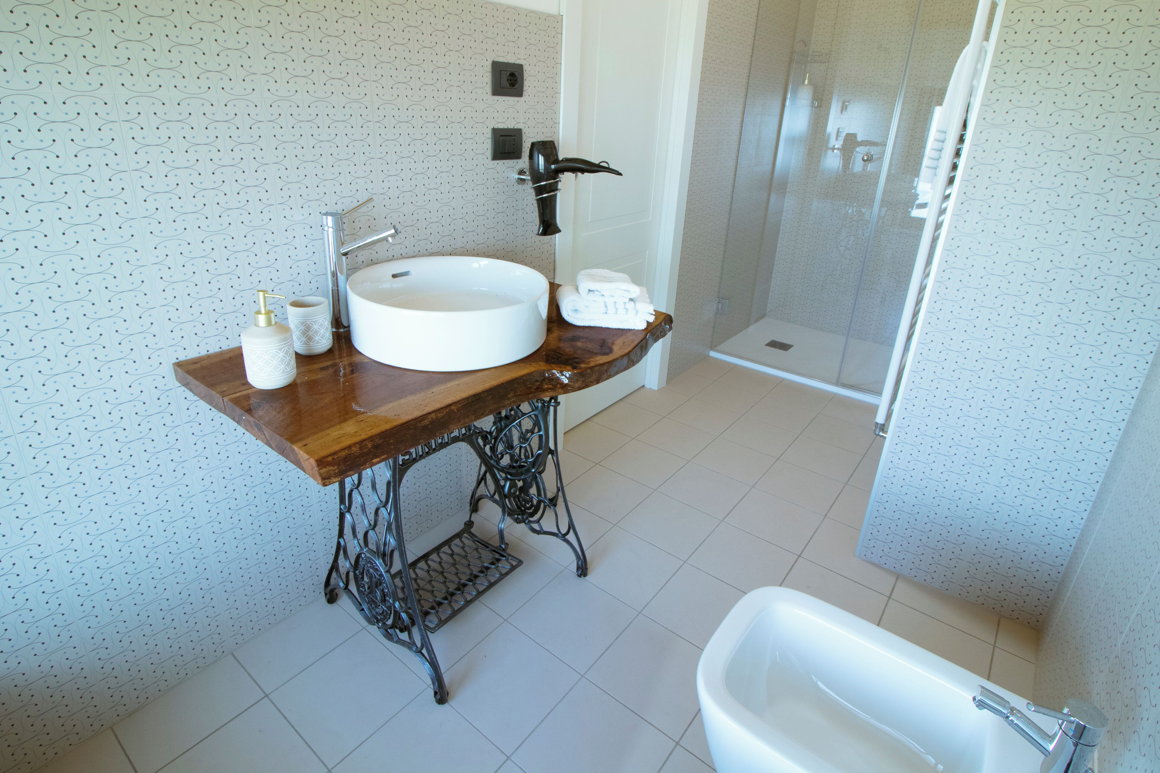 Een badkamer met een houten wastafel, een witte wasbak, een douche en een toilet.