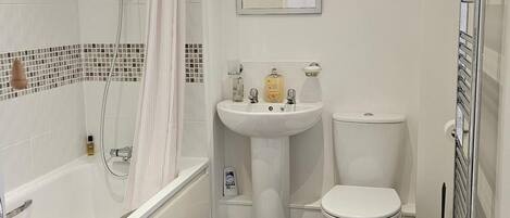 A bathroom with a bathtub, a sink, a toilet, and a shower curtain.