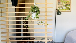 A room with a wooden slatted partition, a bed, a floor lamp, and a framed picture on the wall. - Cosy 3-star house with private garden and quiet terrace (Mézériat)