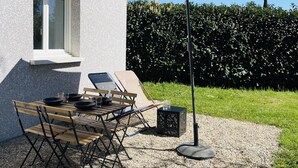 An outdoor patio with a table, chairs, and an umbrella. - Cosy 3-star house with private garden and quiet terrace (Mézériat)