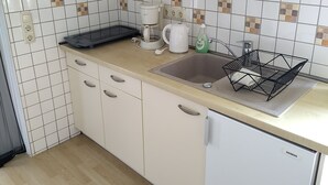 Eine Küche mit weißen Schränken, einer Spüle, einer Kaffeemaschine und einem Siemens Geschirrspüler.