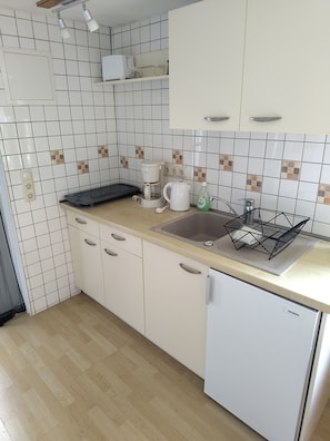 A kitchen with white cabinets, a countertop, a sink, a coffee maker, a kettle, and a Siemens refrigerator. - House Maria Grieben-Hiddensee (Insel Hiddensee)