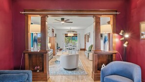 A spacious living area with a wooden floor, a white sofa, a blue armchair, and a dining table with chairs. - Walk to Downtown & Elkhart Lake | Firepit (Elkhart Lake)