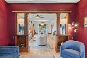 A spacious living area with a wooden floor, a white sofa, a blue armchair, and a dining table with chairs. - Walk to Downtown & Elkhart Lake | Firepit (Elkhart Lake)