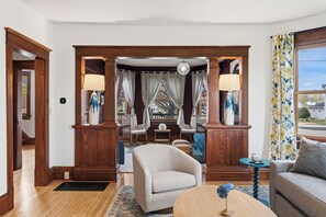 A living room with a wooden archway, a round coffee table, a sofa, and a chair. - Walk to Downtown & Elkhart Lake | Firepit (Elkhart Lake)
