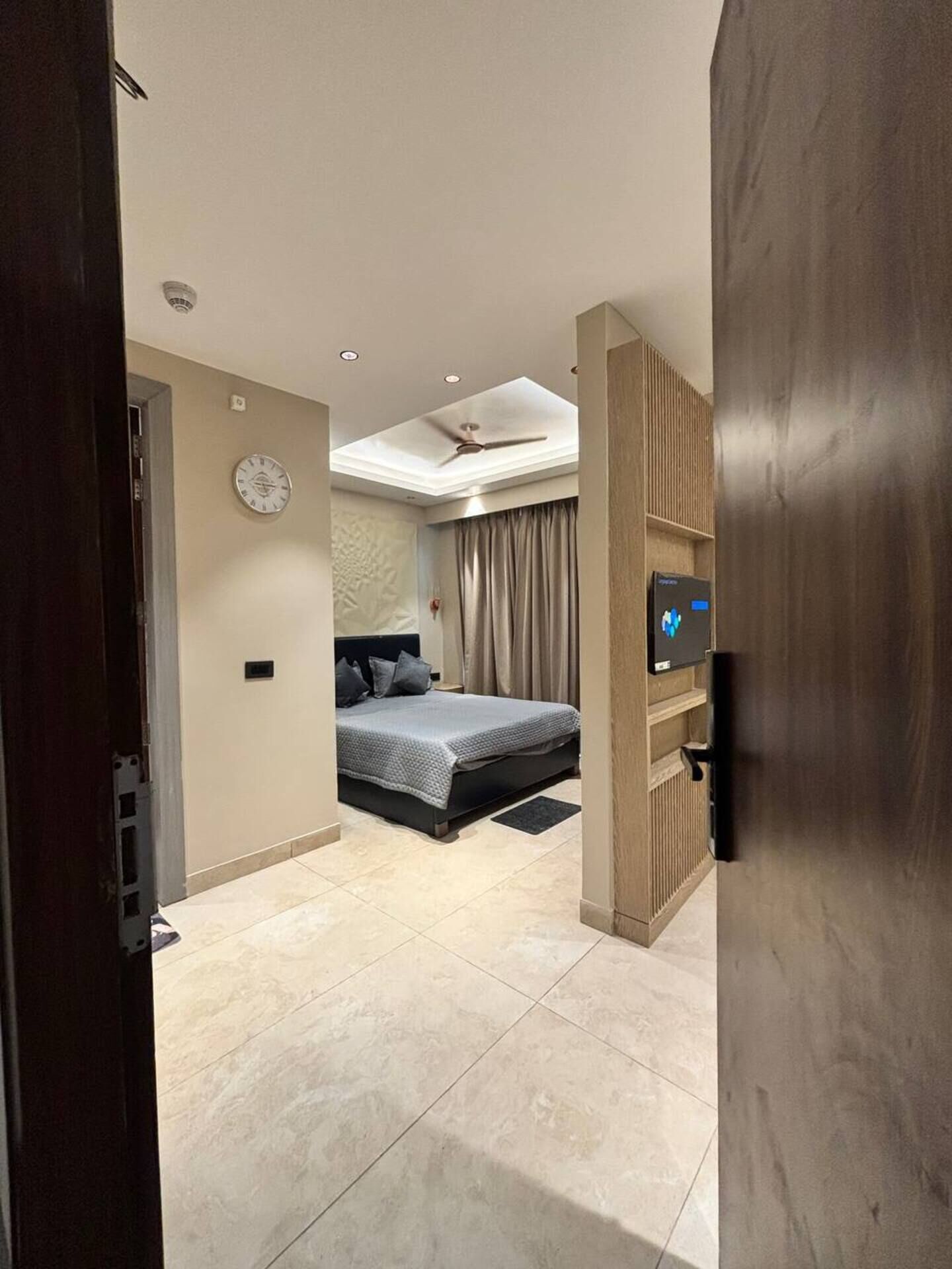 Ein Schlafzimmer mit Bett, Deckenventilator, Uhr und Fernseher.