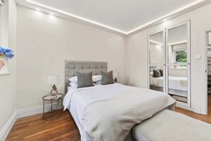 A bedroom with a bed, bedside table, lamp, and a view through a door. - The Garden Gatekeeper- by Out of Office Lifestyle (Greater London)