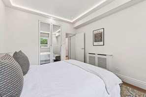 Ein Schlafzimmer mit einem Bett, einem Kleiderschrank, einem Heizkörper und einem gerahmten Bild an der Wand.