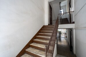 Un escalier avec des marches en marbre et une rampe en bois menant à l’étage supérieur.